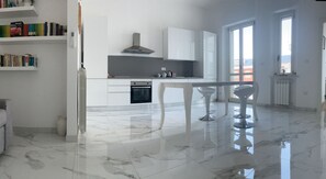 Een moderne keuken met witte kasten, een inbouwoven en een eethoek met twee barstoelen.