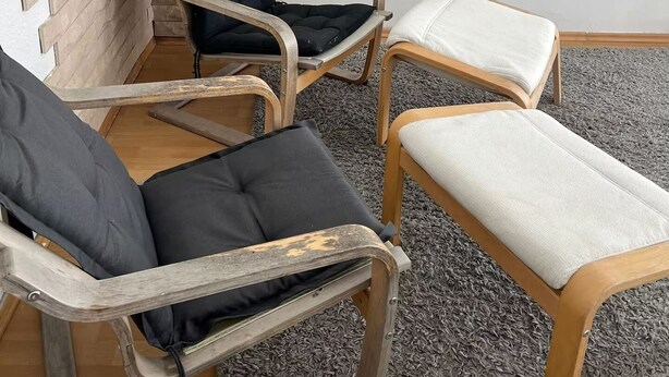 Une pièce avec deux chaises en bois et une petite table, un mur en briques et un mur blanc.