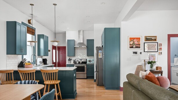 A modern kitchen with teal cabinets, a central island, wooden chairs, and a dining table. - NEW, Designer Home Sleeps 10, King Beds, Deck + Blackstone Grill (Indianapolis)
