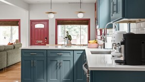 A modern kitchen with teal cabinets, a white countertop, and a coffee maker. - NEW, Designer Home Sleeps 10, King Beds, Deck + Blackstone Grill (Indianapolis)