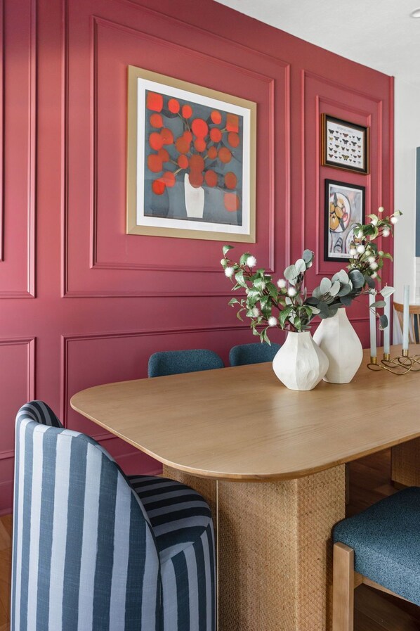 A dining area with a wooden table, striped chairs, and a vase with flowers.