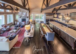 Un vaste espace de vie comprenant un coin salon avec cheminée, une table à manger et une cuisine équipée d’appareils électroménagers modernes.