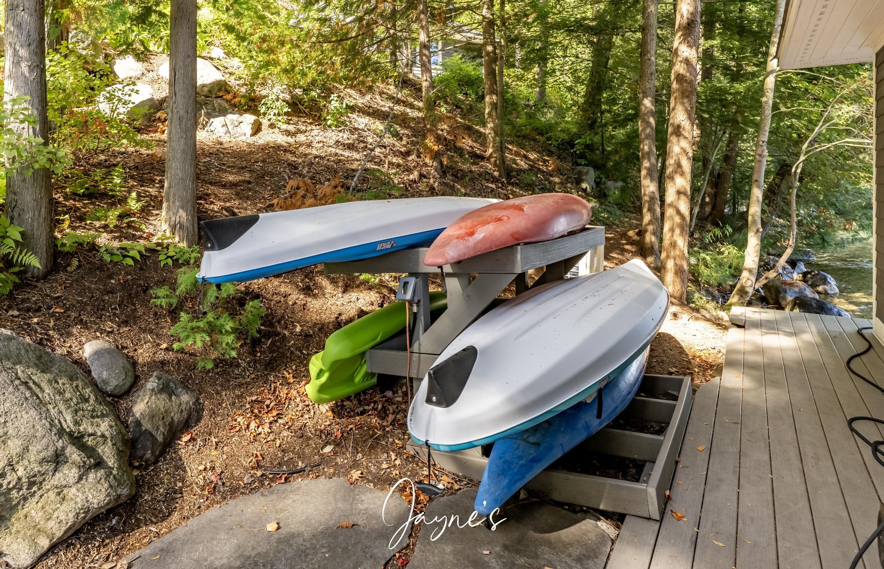 A kayak storage area with two kayaks, one red and one white, on a wooden rack.
