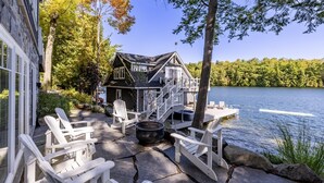 A lakeside cabin with outdoor seating and a fire pit.
