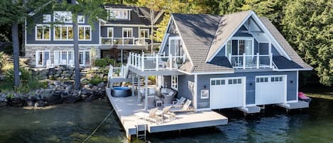 A waterfront property with a dock, a covered outdoor seating area, and a large house with multiple decks.