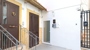 A residential building with numbered doors, a metal staircase, and a gated entrance. - Bed and Breakfast 'Super Luxury' with Private Garden, Wi-Fi and Air Conditioning (Massafra)