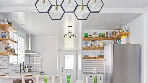 Una cocina moderna con armarios blancos, una mesa de comedor de madera y una araña.