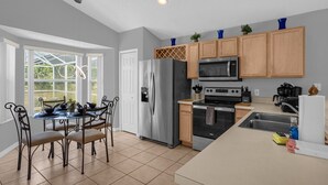 A modern kitchen with a dining area, featuring a stainless steel refrigerator, a microwave, an oven, and a sink. - 4 Bedroom home with games room & pool in gated community (Davenport)