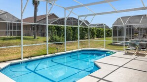 A swimming pool with a glass enclosure, surrounded by a lawn and a view of houses. - 4 Bedroom home with games room & pool in gated community (Davenport)