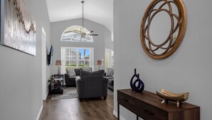 A modern living room with a grey sofa, a wooden console table, and a decorative mirror. - 4 Bedroom home with games room & pool in gated community (Davenport)