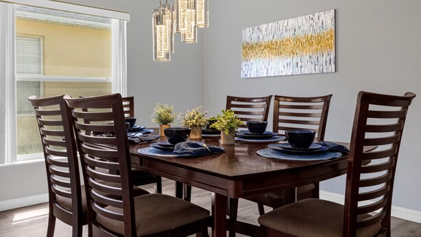 A dining area with a wooden table, six chairs, and a chandelier. - 4 Bedroom home with games room & pool in gated community (Davenport)