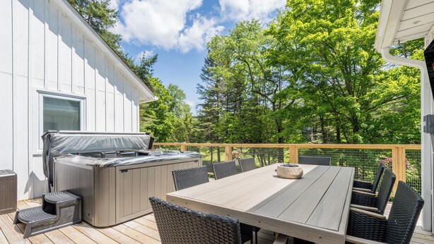 Eine Terrasse im Freien mit Holztisch und -stühlen, einem Grill und einem Whirlpool.
