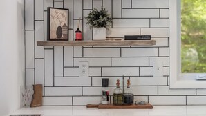 Eine Küche mit weiß gefliestem Fliesenspiegel, Holzregalen und verschiedenen Küchenutensilien.