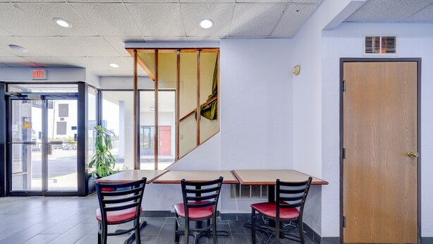 A modern interior with a wooden door, a glass entrance, and a seating area with chairs and a table.