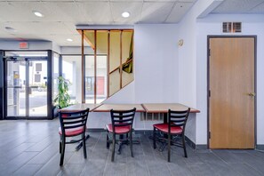 En modern interiör med en trädörr, en entré med glasparti och en sittgrupp med stolar och ett bord.