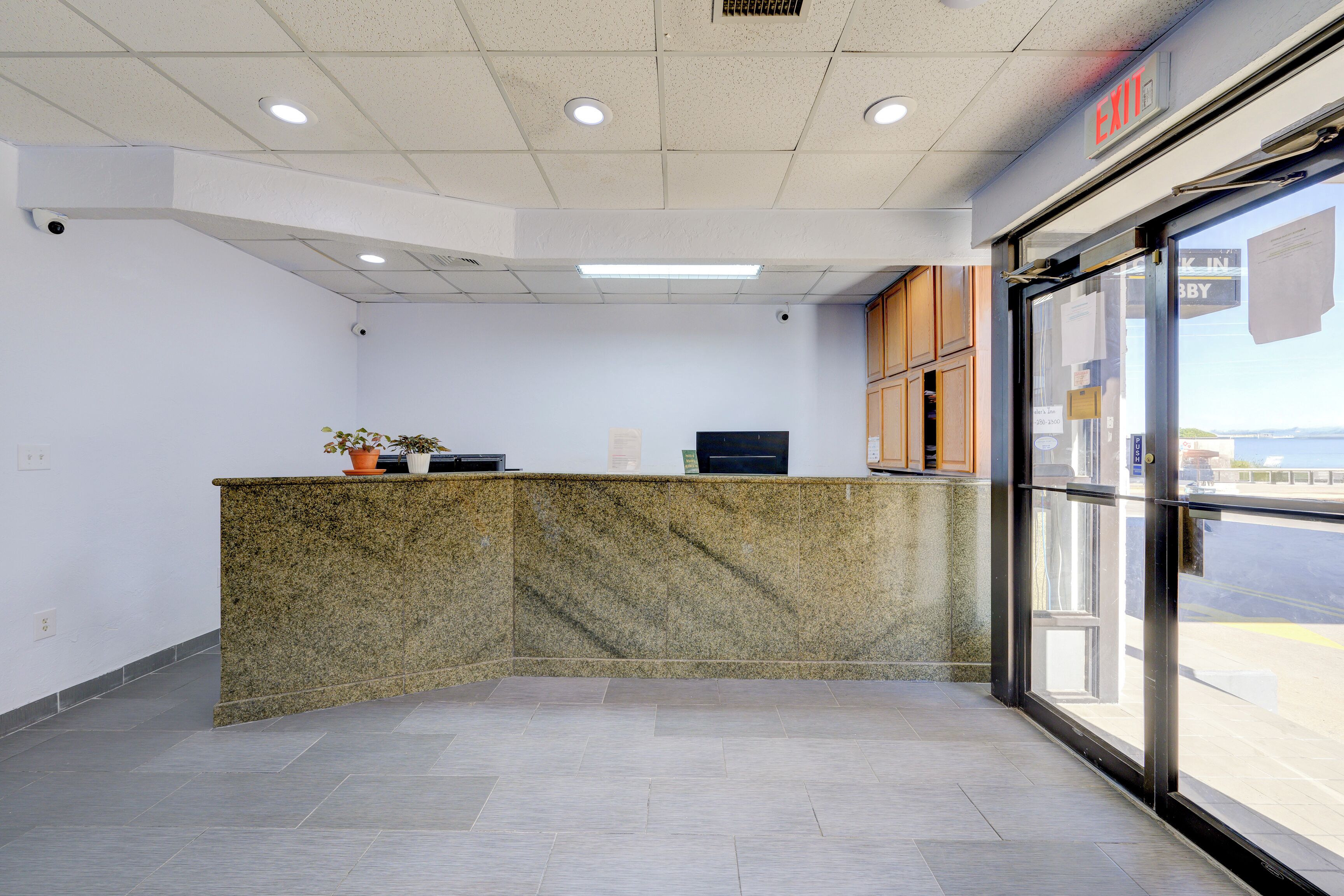 A reception area with a granite counter, a potted plant, and a glass door leading outside.