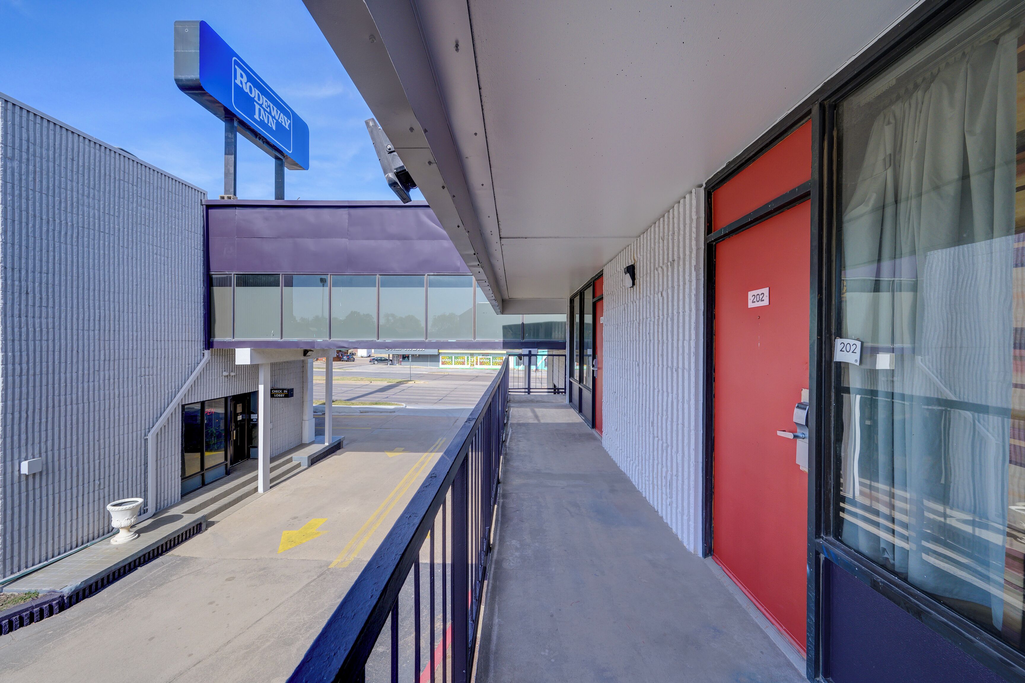 A hotel exterior with a modern design, a covered walkway, and a clear view of the parking lot.