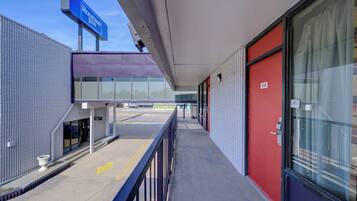 A hotel exterior with a modern design, a covered walkway, and a clear view of the parking lot.