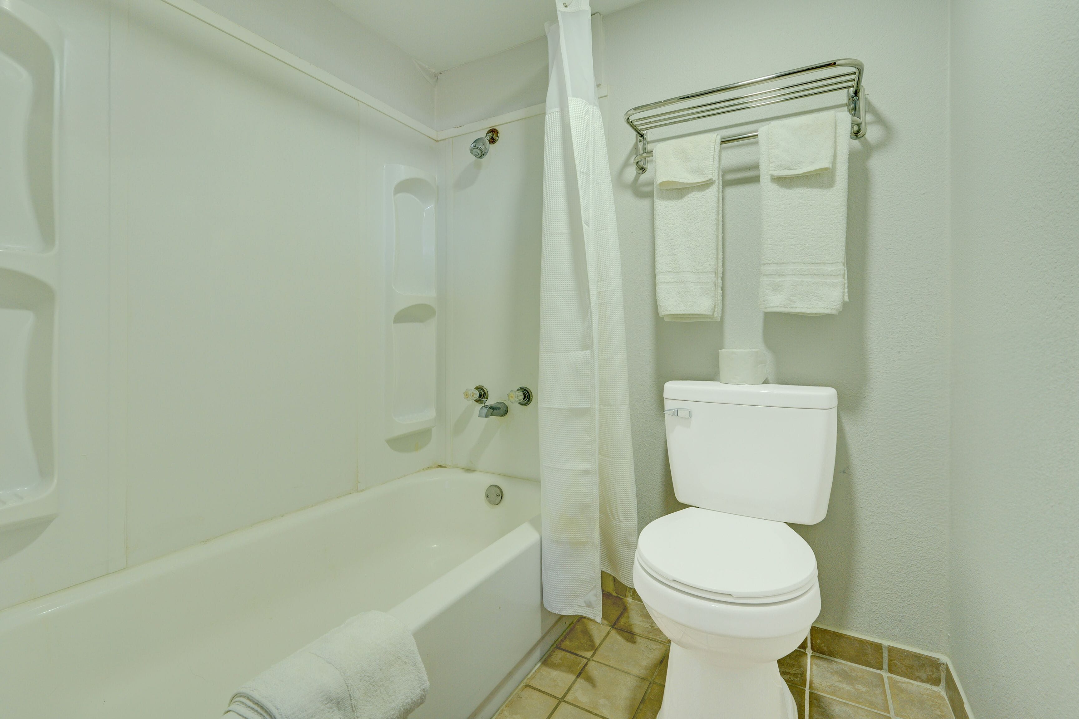 A bathroom with a bathtub, toilet, and a shower curtain.
