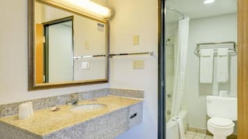 Een badkamer met een wastafel met granieten blad, een spiegel met gouden lijst, een handdoekrek met witte handdoeken en een wit toilet.