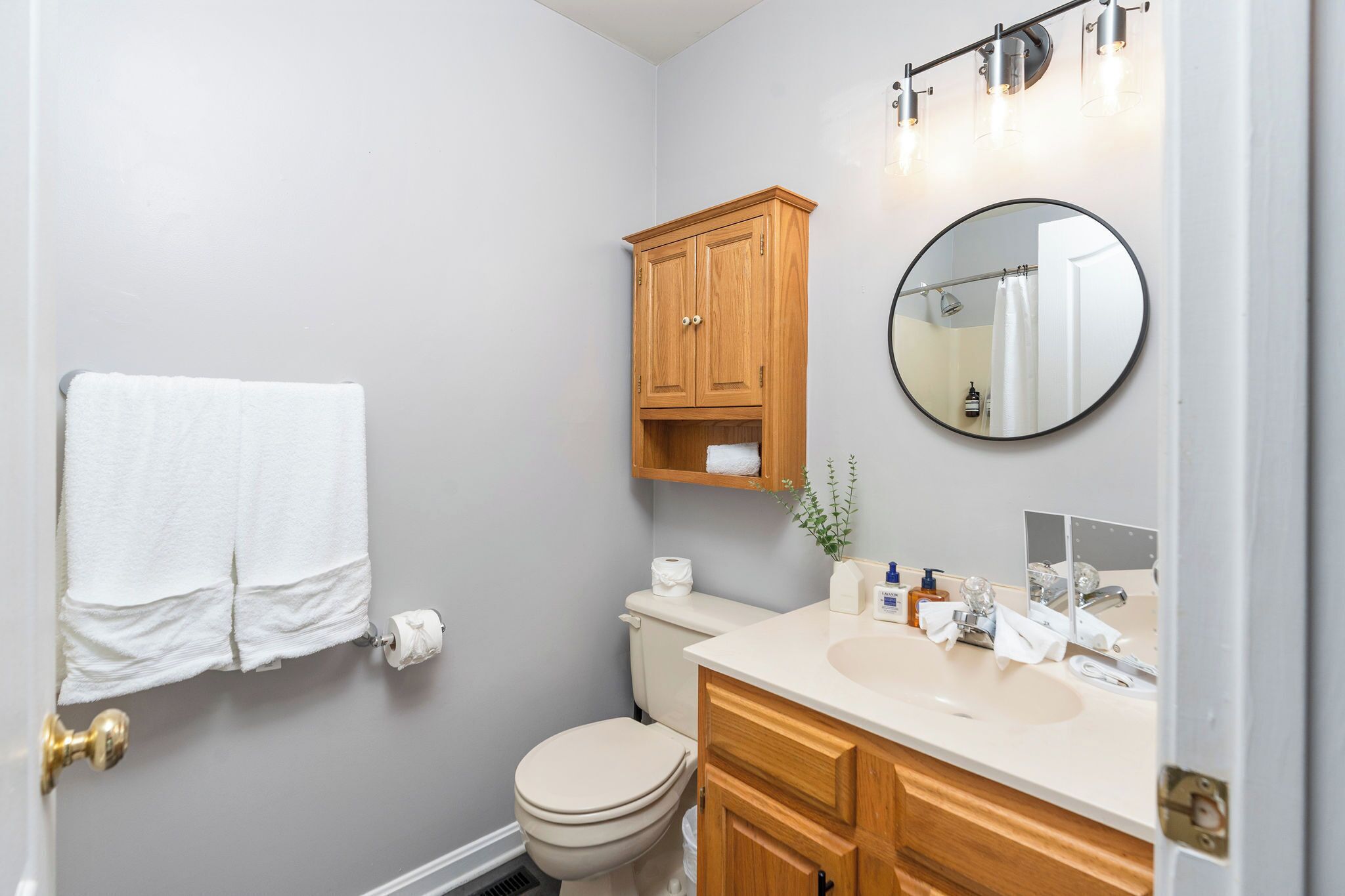 Une salle de bain avec des toilettes, un lavabo avec un miroir et une serviette accrochée au mur.