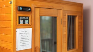 Sauna, jossa on ohjauspaneeli, turvallisuusvaroituskyltti ja puuovi.