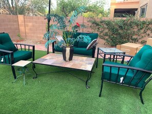 Een terras met groene stoelen, een tafel en een plant in pot.