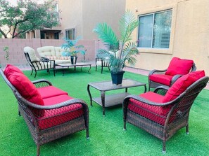 A patio with wicker furniture, a small table, and potted plants.