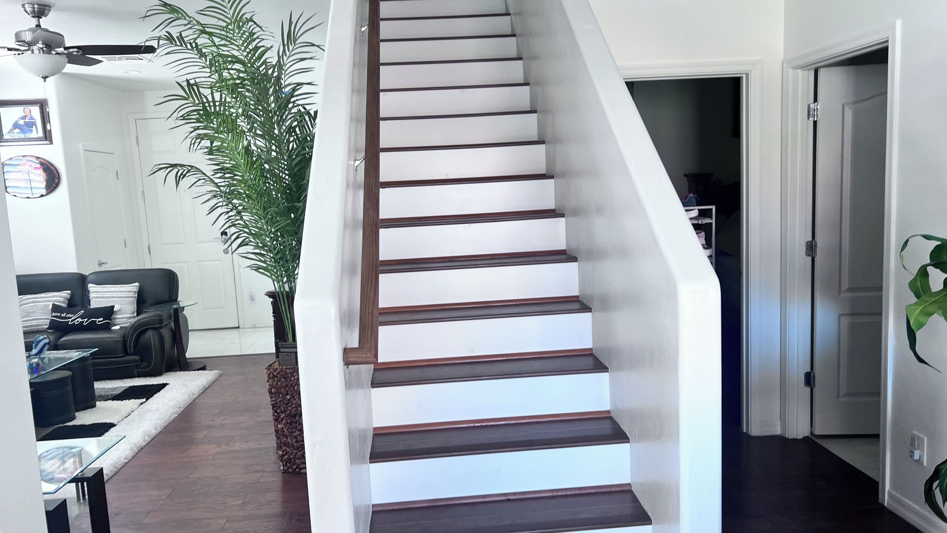 A staircase with wooden steps and white walls, leading to a hallway with a door.
