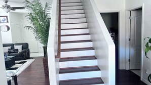 Eine Treppe mit Holzstufen und weißen Wänden, die zu einem Flur mit einer Tür führt.