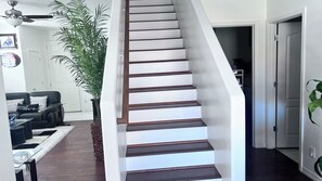 A staircase with wooden steps and white walls, leading to a hallway with a door. - Spacious 5-bedroom house in gorgeous Tucson with AC (Tucson)