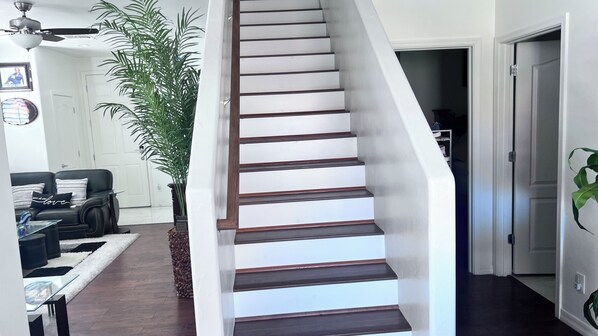 A staircase with wooden steps and white walls, leading to a hallway with a door.