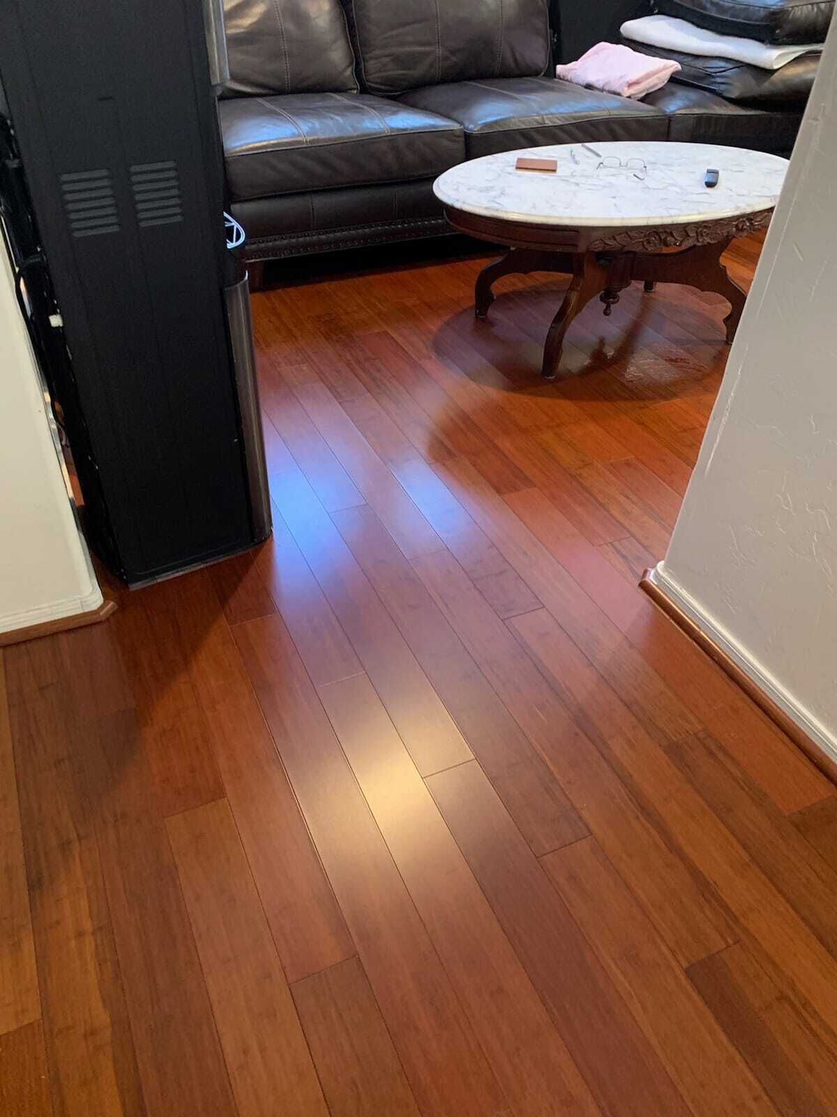 Ein Zimmer mit Holzboden, einem schwarzen Sofa und einem runden Couchtisch.