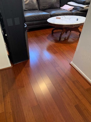 A room with a wooden floor, a black sofa, and a round coffee table.