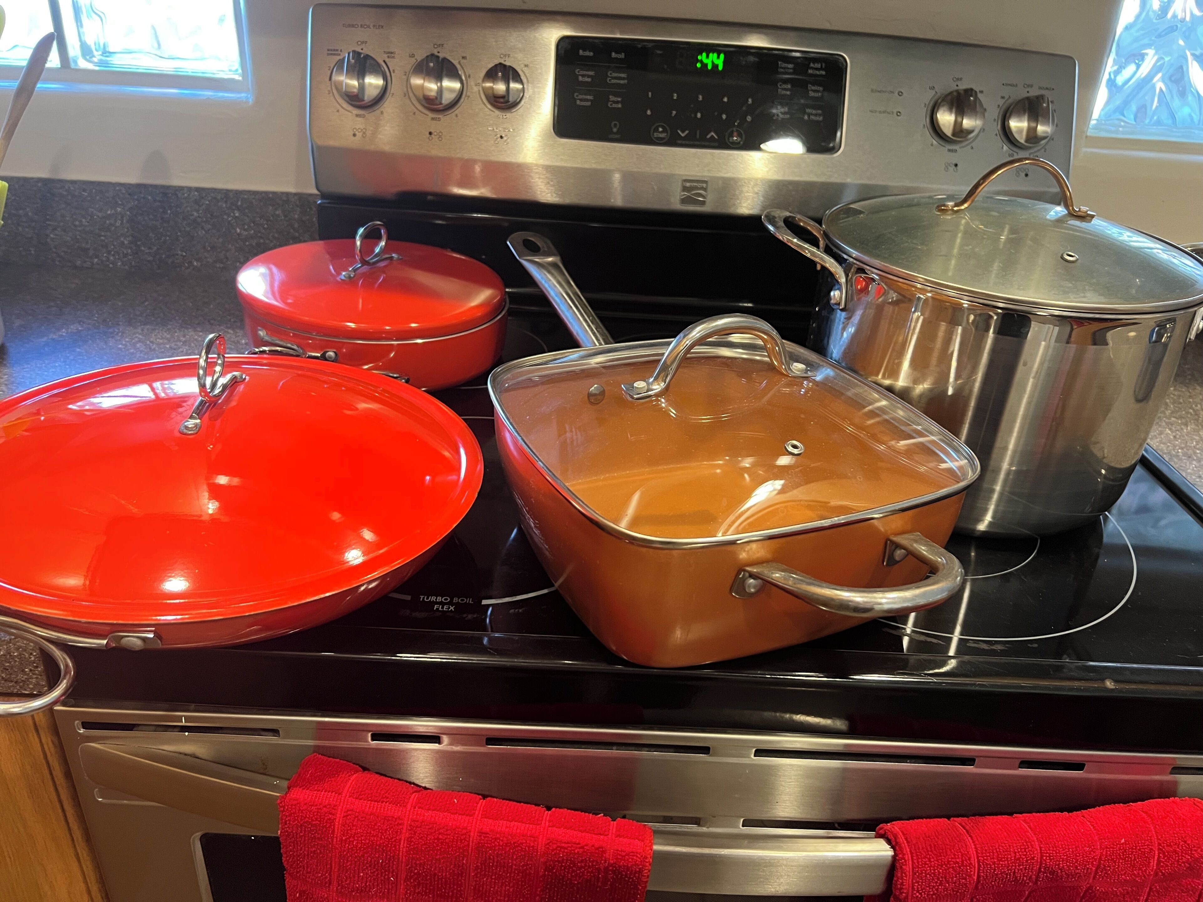 Uma cozinha com fogão, panelas e um rel ógio digital.