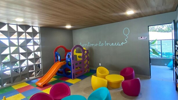 Een speelruimte voor kinderen met een glijbaan, kleurrijk speelgoed en zachte zitplaatsen.