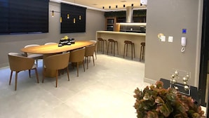 Een moderne keuken met een centraal eiland, hanglampen en een eethoek met een ronde tafel en stoelen.