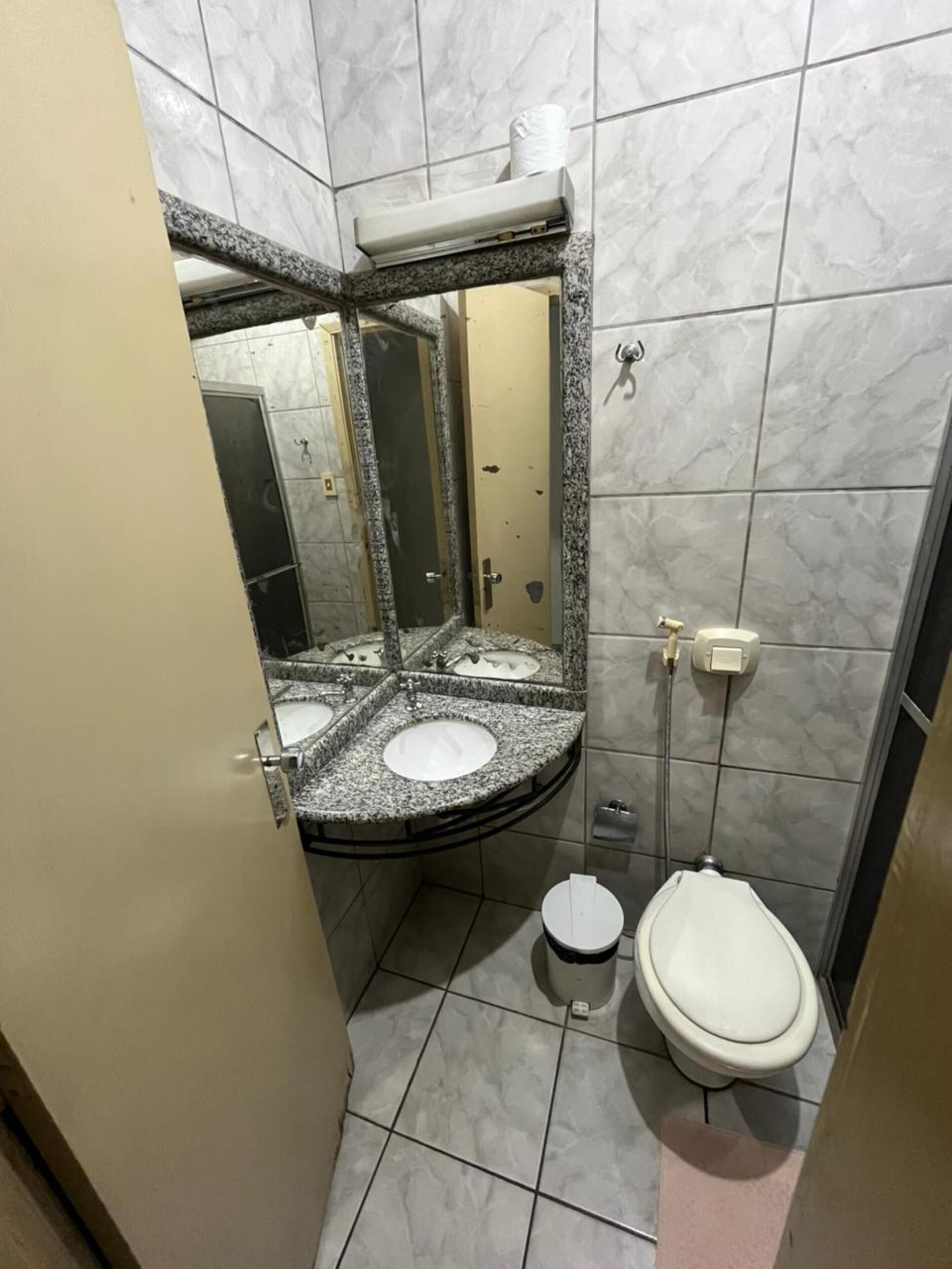 Een badkamer met een betegelde vloer van marmer, een wastafel met spiegel, toilet en douche.