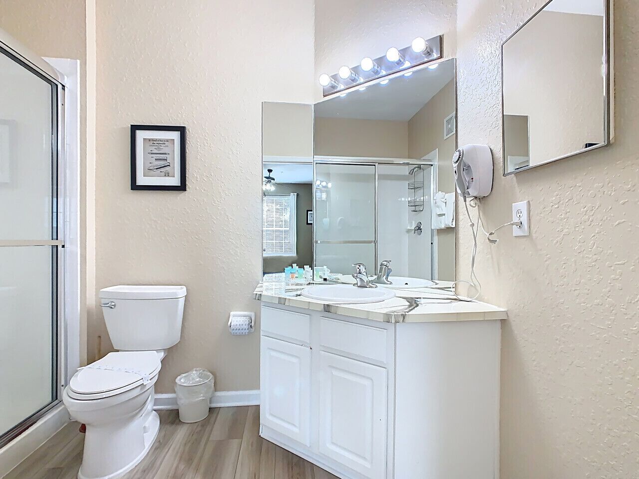 Une salle de bain comprenant des toilettes, un lavabo, un miroir et une douche.