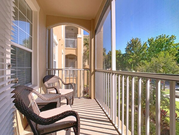 A balcony with wicker furniture and a view of a residential building.