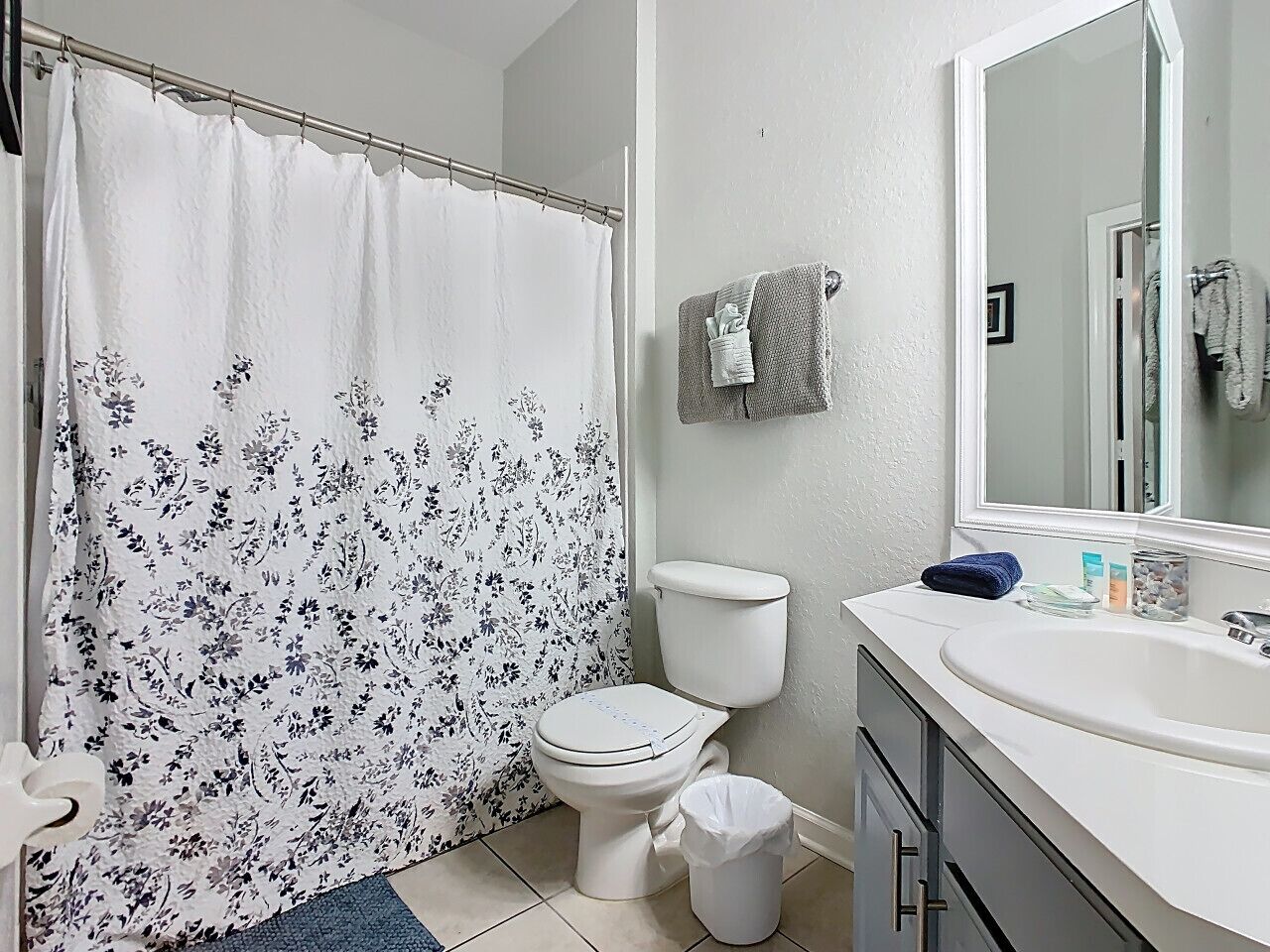 Une salle de bain équipée d’un rideau de douche, de toilettes, d’un lavabo et d’un miroir.
