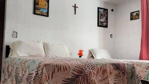 A bedroom with a bed, a cross on the wall, and a framed picture. - Quiet and beautiful apartment (Orizaba)