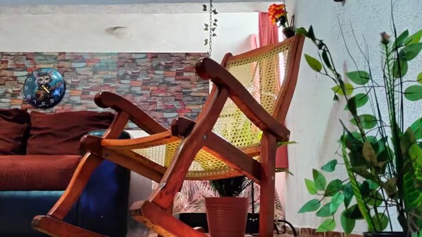 A living room with a wooden rocking chair, a brick-patterned wall, a blue sofa, and a potted plant. - Quiet and beautiful apartment (Orizaba)