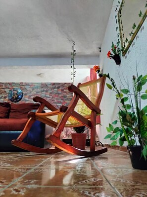 A living room with a wooden rocking chair, a brick-patterned wall, a blue sofa, and a potted plant. - Quiet and beautiful apartment (Orizaba)