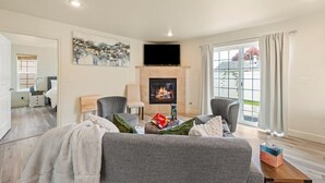 A living room with a fireplace, two armchairs, a sofa, and a television.