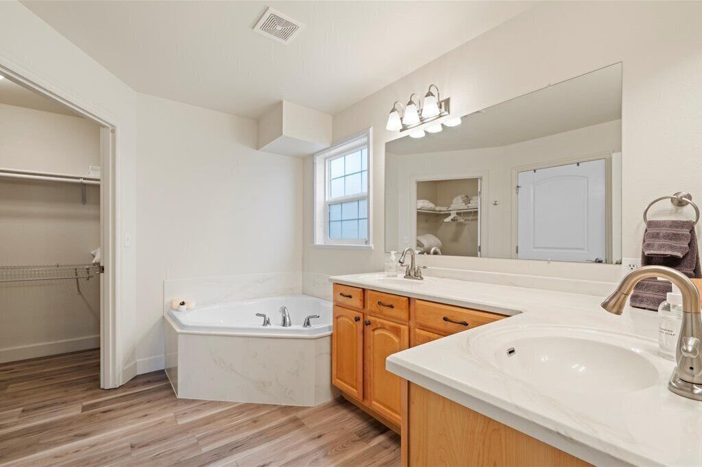 A modern bathroom with a bathtub, a vanity with a sink, and a large mirror.