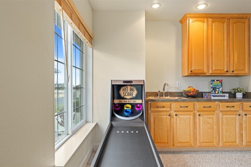 A kitchen with wooden cabinets, a window, and a bowling lane.