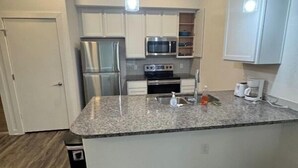 A modern kitchen with white cabinets, stainless steel appliances, and a granite countertop. - Cozy 1BR Apartment with Kitchen in Leander Tx. (Leander)