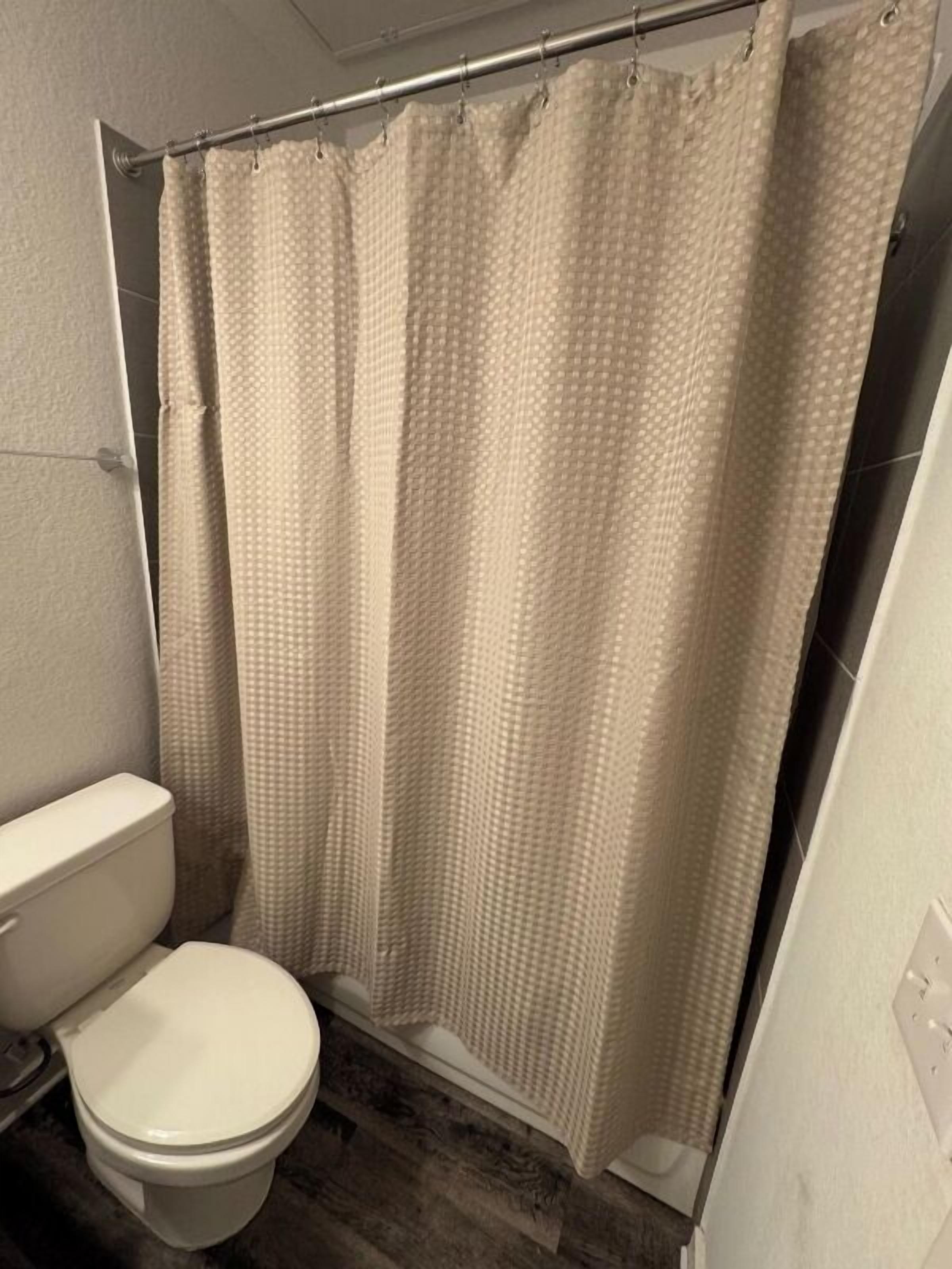 Une salle de bain avec des toilettes, un rideau de douche et une baignoire.