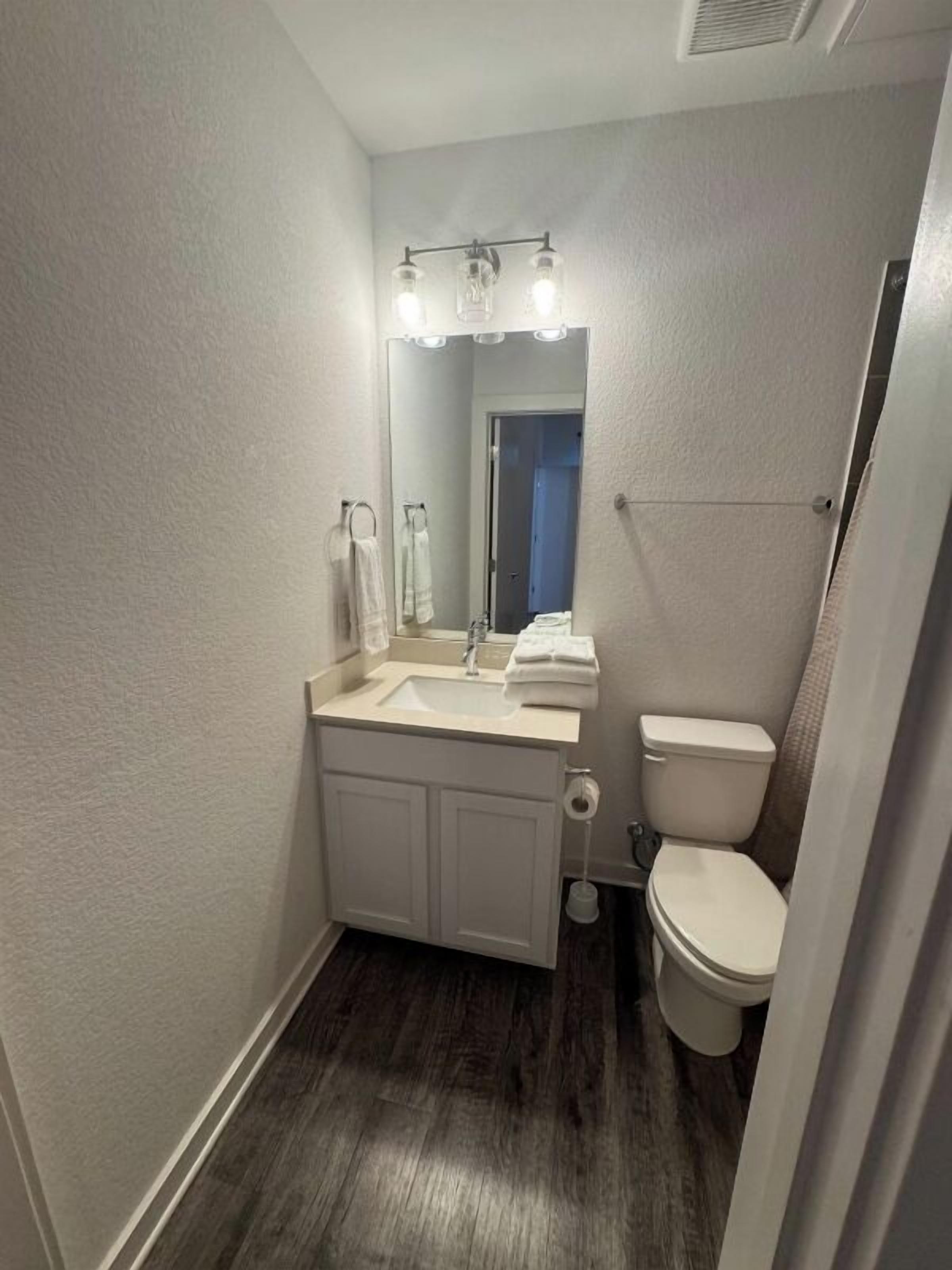 A small, compact bathroom with a white sink, mirror, and toilet.